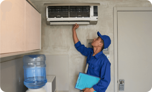 Technician inspecting air conditioner in office.