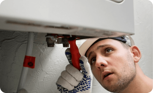 Technician repairing a boiler with a wrench