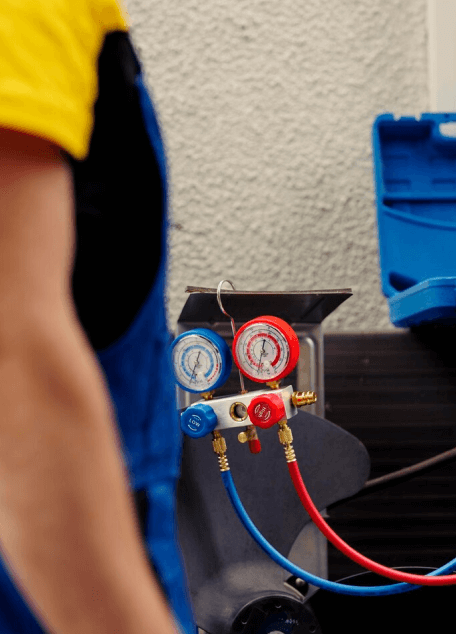 Technician with HVAC pressure gauges on equipment.