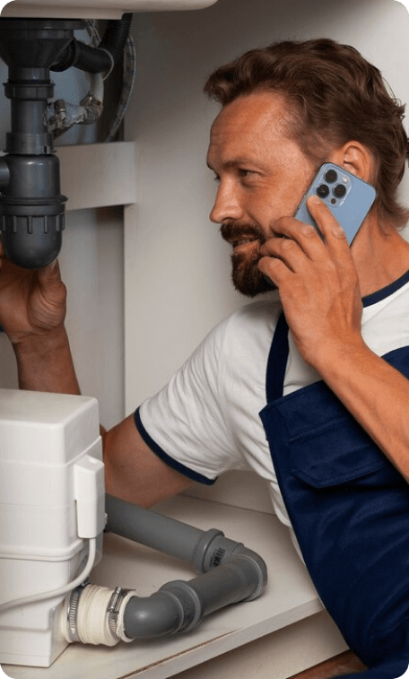 Plumber fixing sink while on phone call